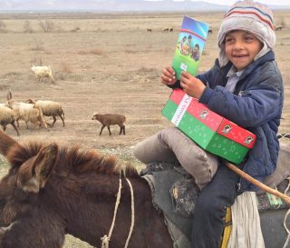 This Central Asian shepherd boy is delighted to receive a gift-filled shoebox and a copy of The Greatest Gift Gospel booklet from an Operation Christmas Child volunteer team.