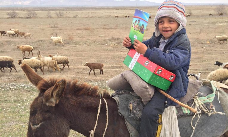 Este niño pastor de Asia Central está feliz de recibir una caja de regalos y una copia de El Mejor Regalo de parte de un voluntario de Operation Christmas Child