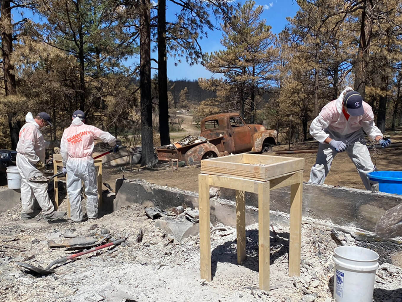Volunteer teams wear suits and masks as they sift through ashes for homeowners' belongings.