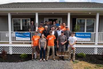 Volunteers, staff, family, and friends join Thomas in celebrating the dedication of his newly constructed home.