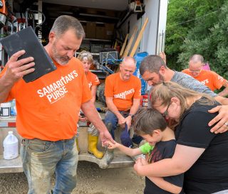 Volunteers pray with the Bankses after dedicating a special Bible to the family signed by the team.