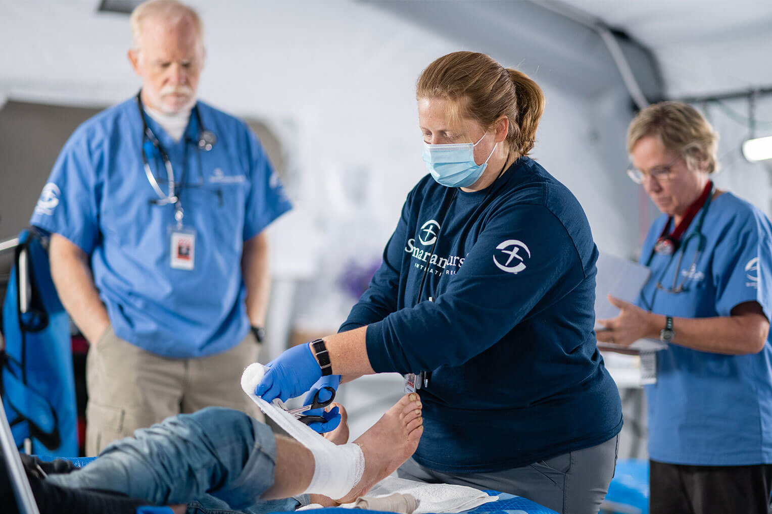 Staffer bandages a foot in Emergency Field Hospital
