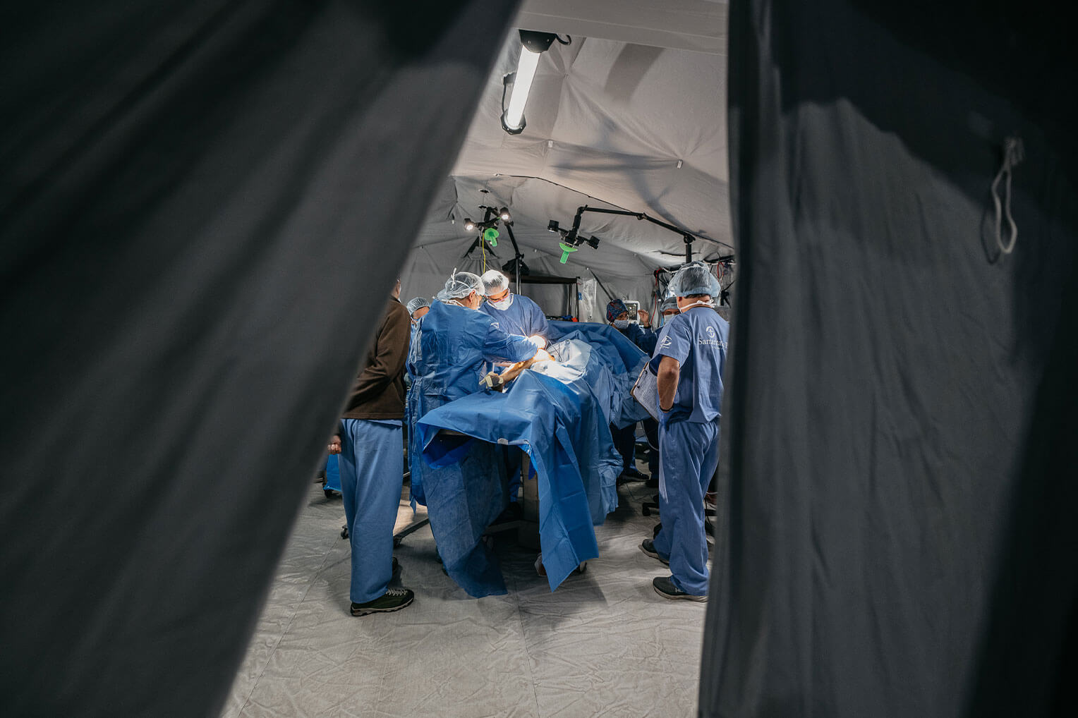Glimpse into active operating room between two black curtains.