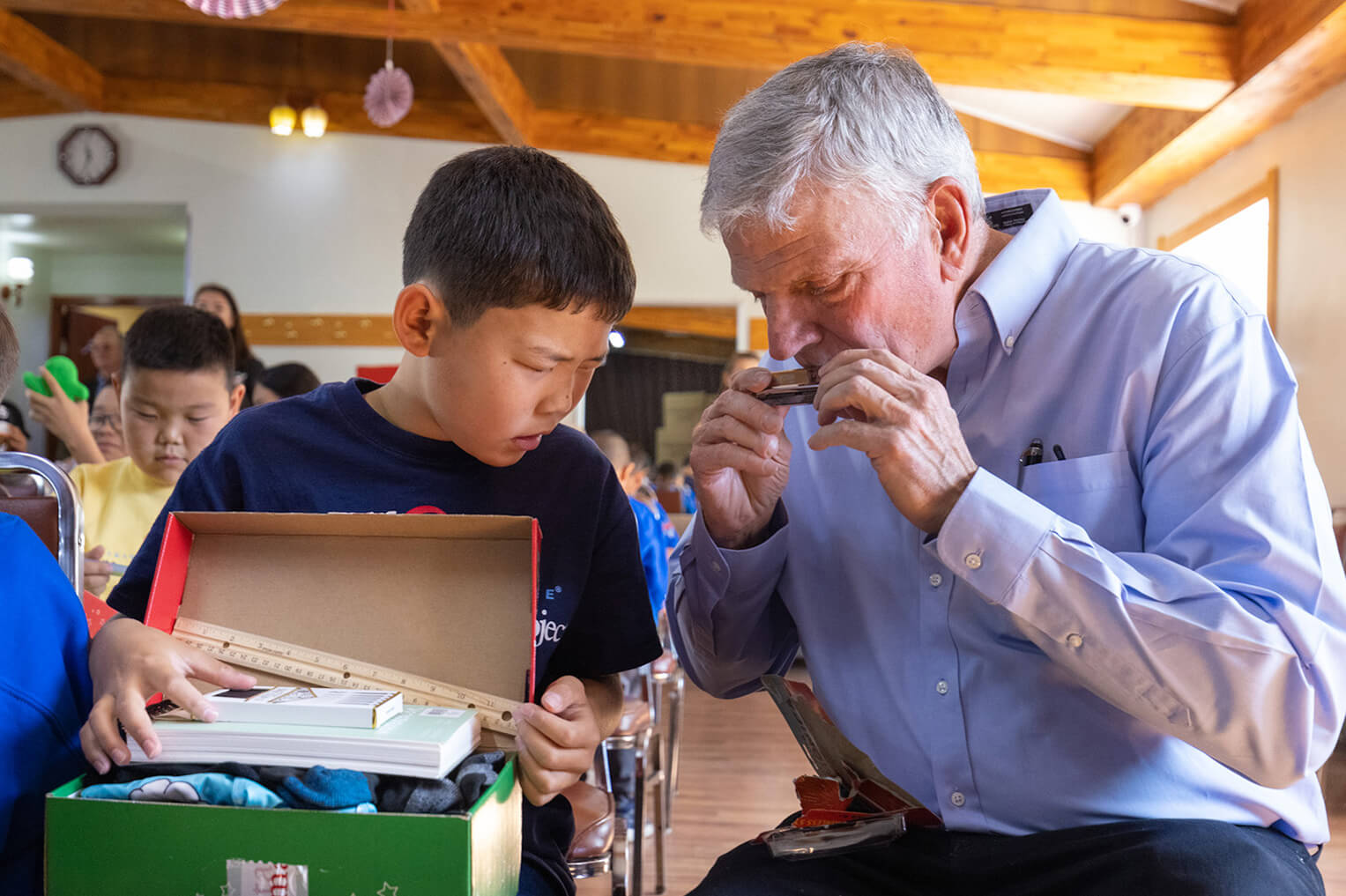 Franklin Graham shows Erdembayar how to work the harmonica that came in his Operation Christmas Child shoebox gift.