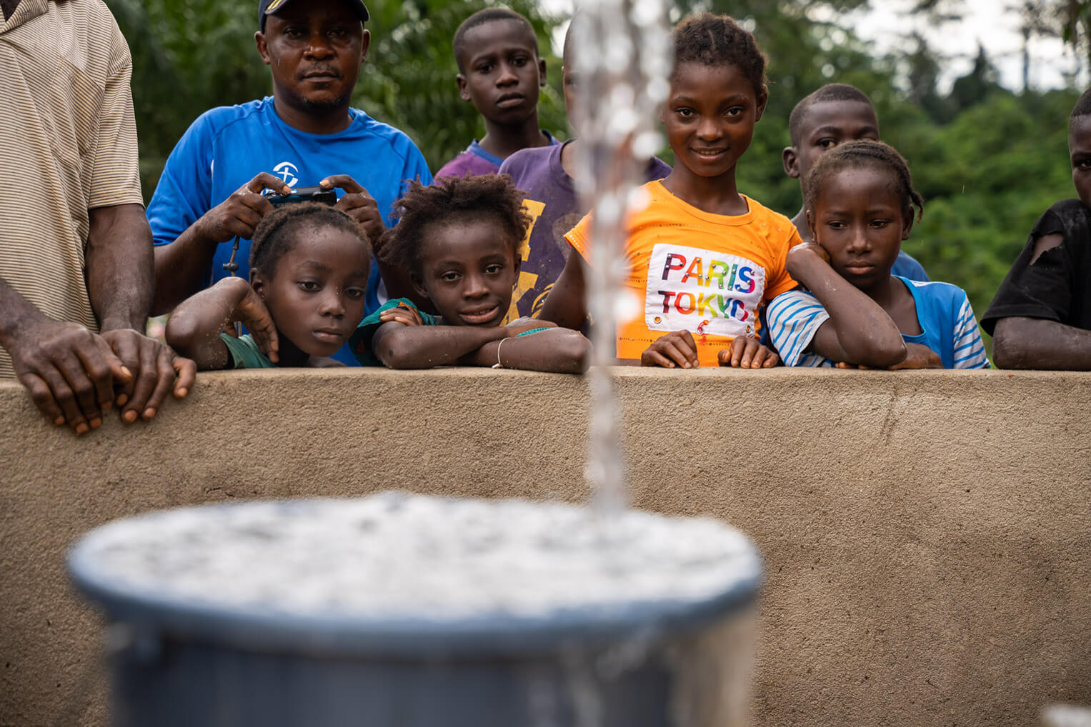 Children in River Gee watch a bucket fill with water from the newest well in the region.