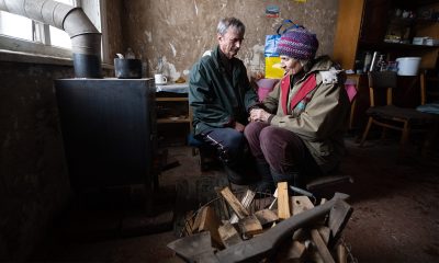 Couple huddles around a wood stove from Samaritan’s Purse.