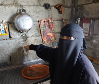 Yemeni woman pours water in her home.