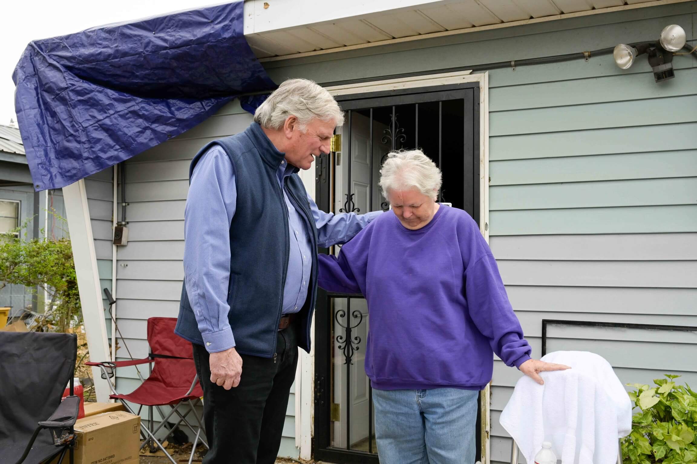 Franklin Graham prays with homeowner Liz Estes after hearing her harrowing experience with the storm.