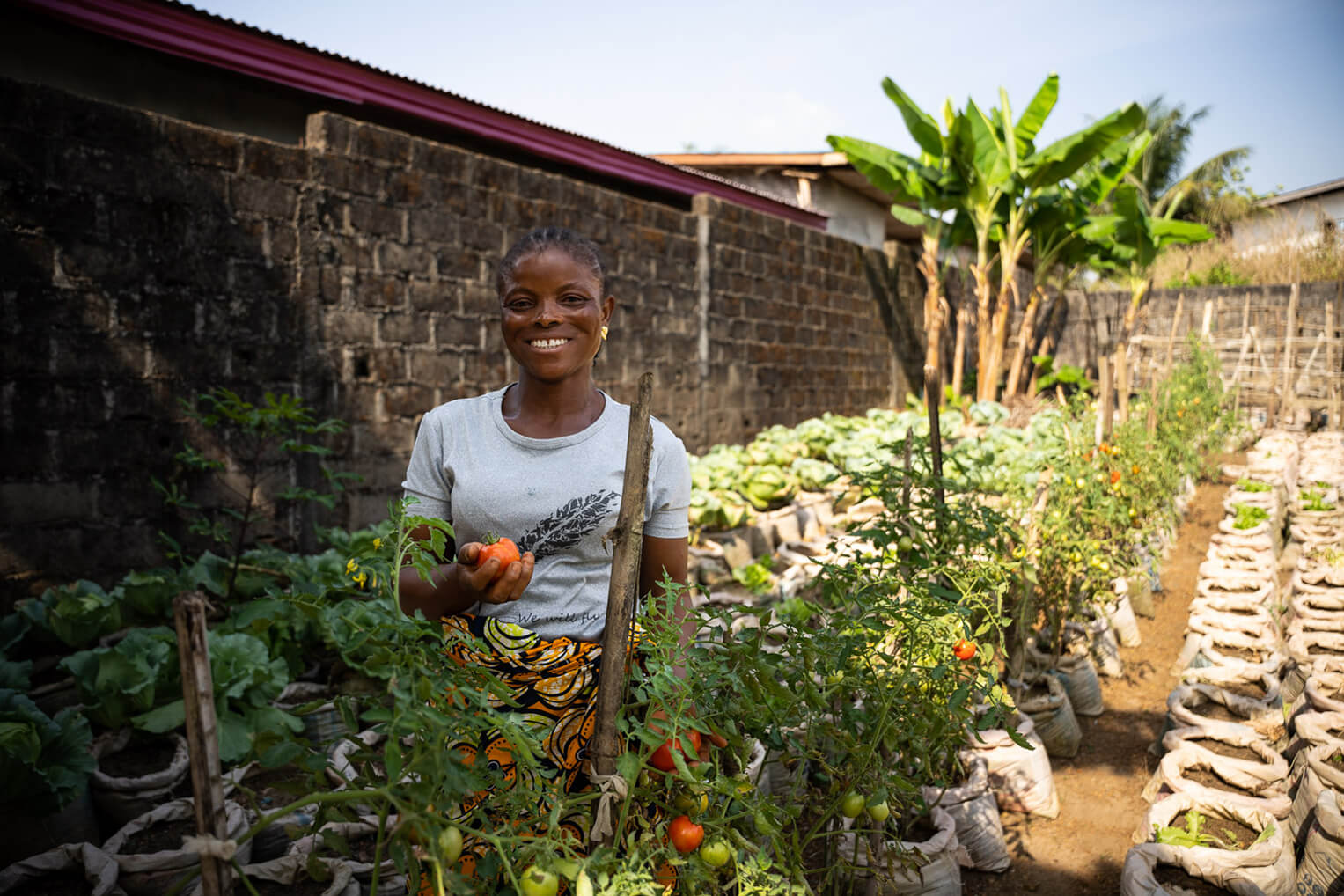 Marthaline, otra participante del Proyecto Edén, se ha entusiasmado mucho con aprender mejores prácticas agrícolas. Aquí está celebrando las cosechas de tomates y de pelotas amargas.