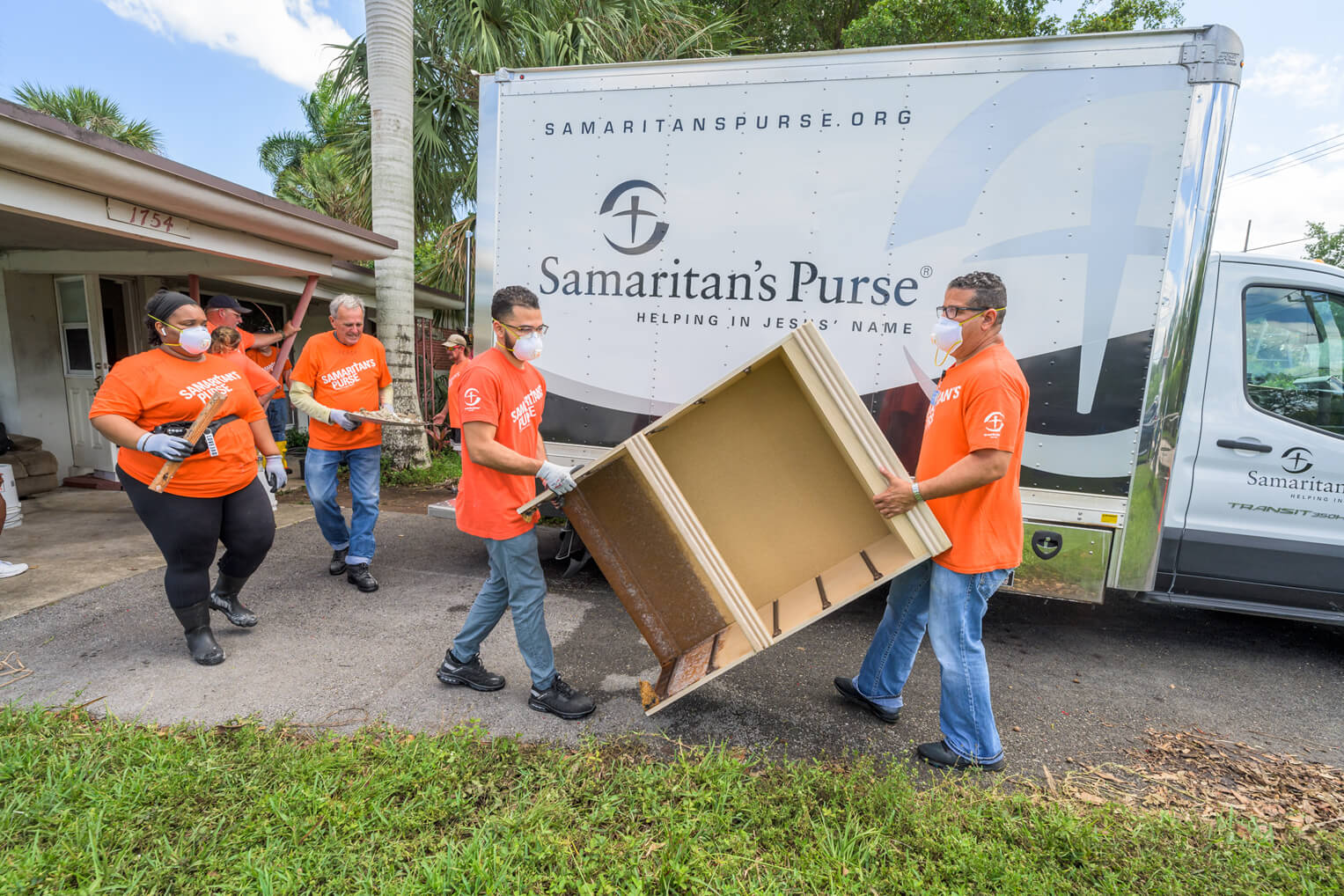 Los voluntarios cargan las cosas pesadas para ayudar a Paul con el proceso de recuperación por la inundación.