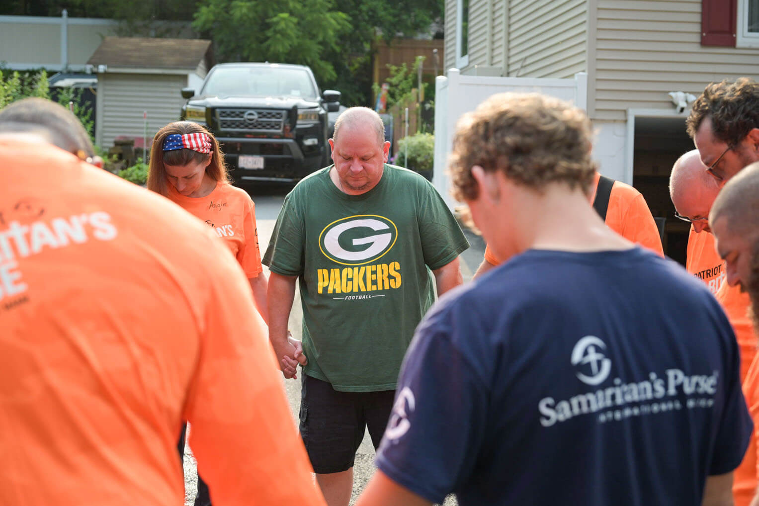 Volunteers pray with homeowner Joe Bartel after helping him clear his flooded home.