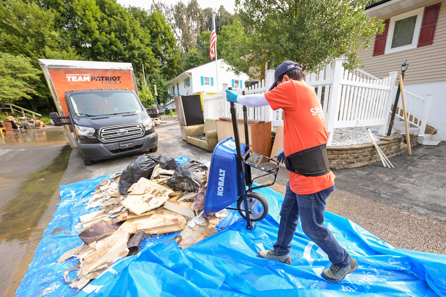 Volunteers carry ruined walls and flooring and other debris to the street.