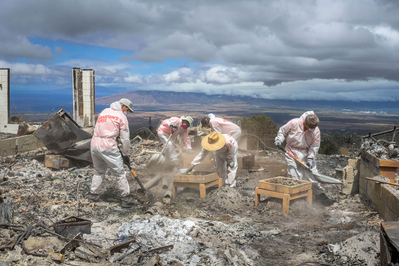 In Tyvek suits, masks, and goggles, Samaritan's Purse volunteers work amid the ruins and ashes of a former home.