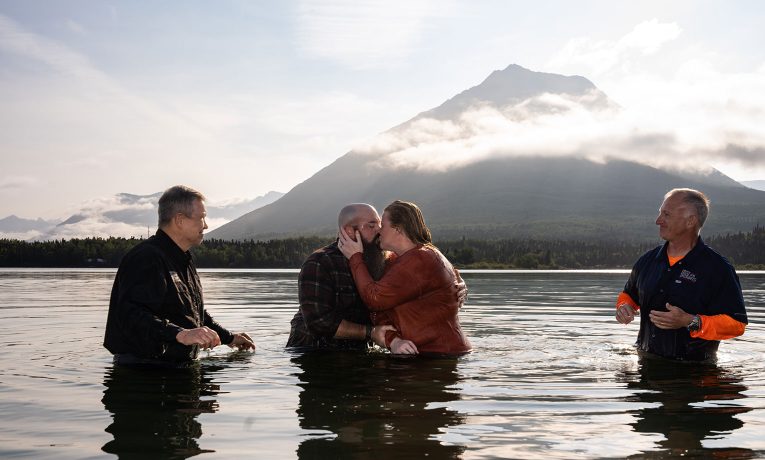 A military couple embraces in the chilly, glacier-fed waters of Lake Clark after their baptism on a bright Friday morning. Retired Army Staff Sergeant Ray Davis and his wife Rebecca attended Operation Heal Our Patriots in Alaska recently.