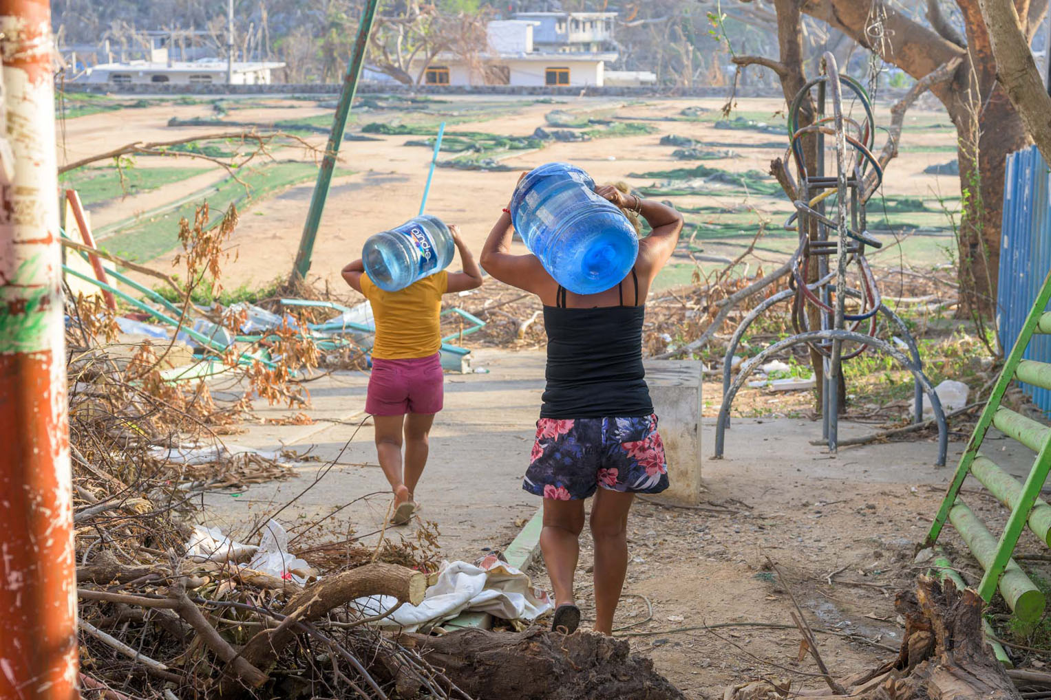 Two women carry home large bottles of water provided through the filter systems established by Samaritan's Purse.