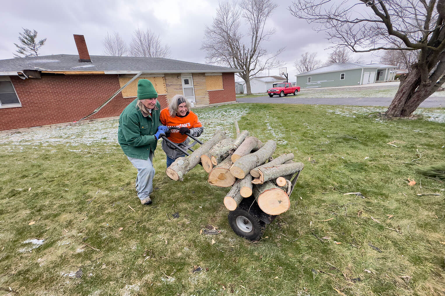 Cathy Douthwaite, right, works joyfully in the cold hauling a cut tree to the street.