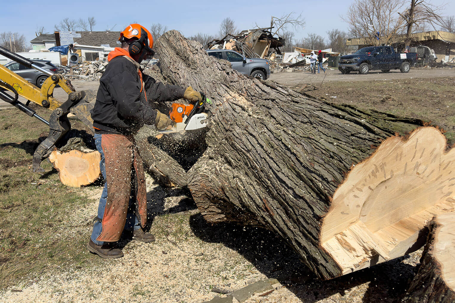 A volunteer cuts up the last of a large storm-damaged oak that threatened to fall on Jenny Leiter's home.