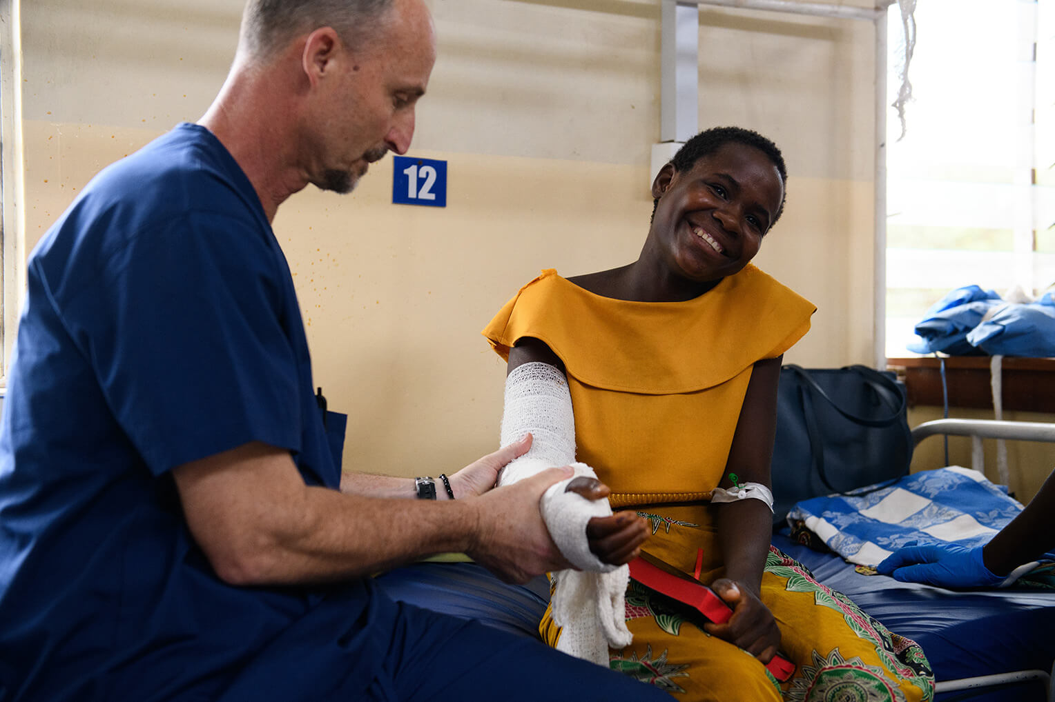 Kemp Laidley, a physical therapist with Samaritan's Purse, helps Ireen after her surgery. Despite the pain, Ireen still smiles.