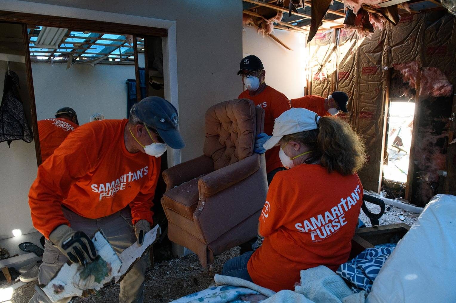 Los voluntarios toman el tiempo para rescatar posesiones que quedan tiradas entre la destrucción.