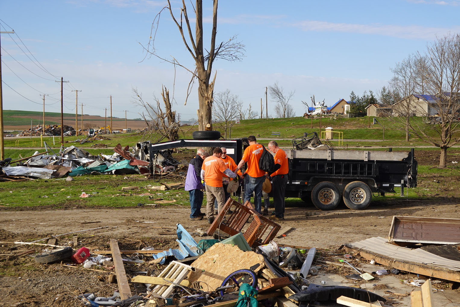 Volunteers join in prayer in the Minden neighborhood where twisters ripped up trees and homes.