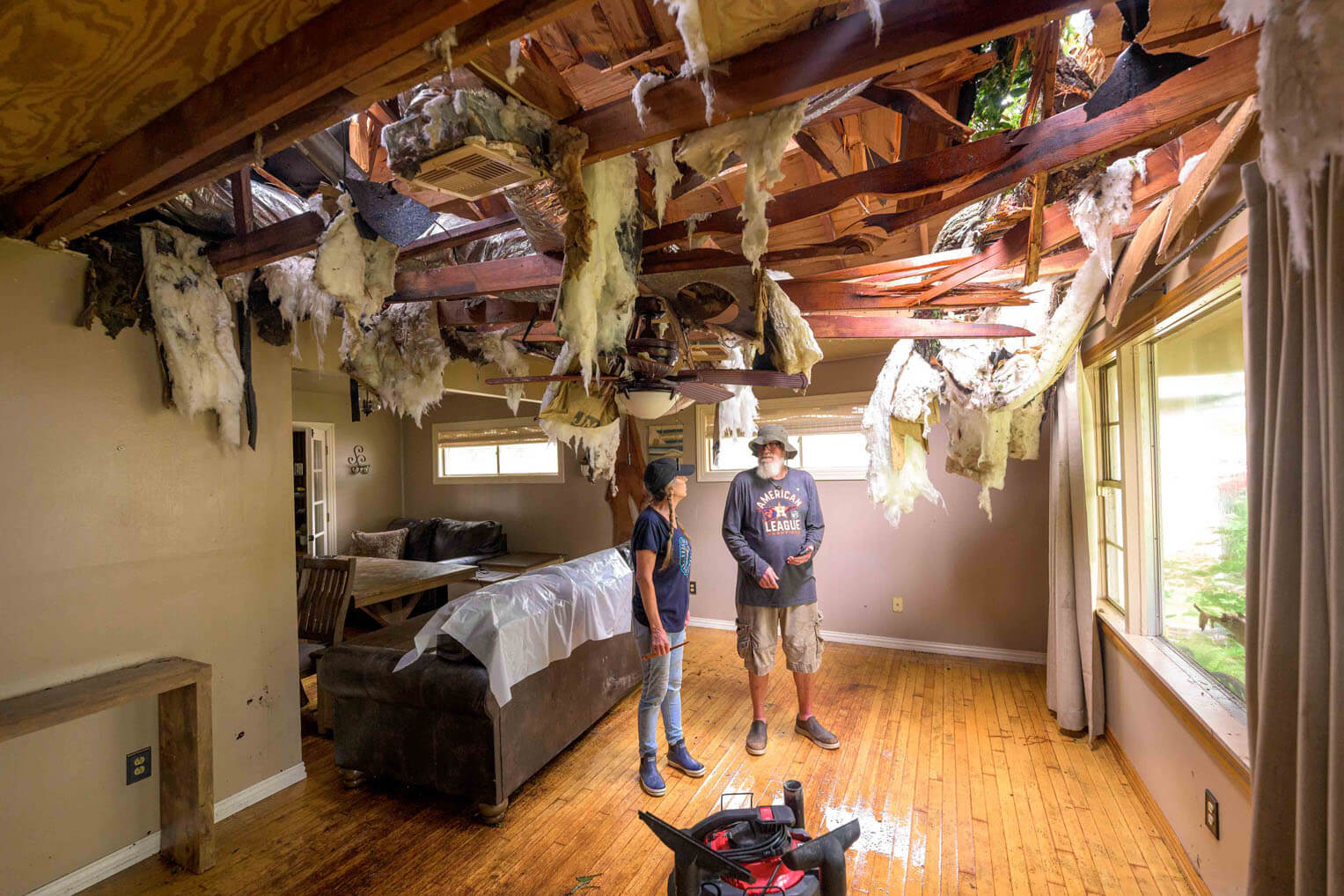 Tim and Leslie Burch stand surveying the gapping tear in their ceiling from a tree that Hurricane Beryl blew over on their house.