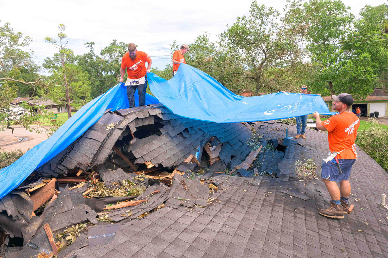 Samaritan's Purse volunteers tarp the Burch's roof after a tree collapsed on it during the storm. Thousands of other homes experienced similar damage to their properties. 