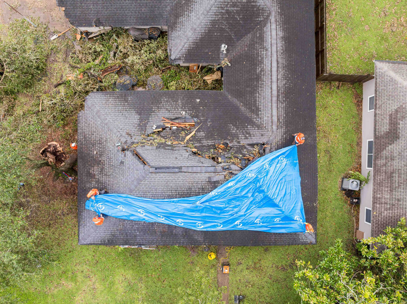 Samaritan's Purse volunteers install a tarp to cover an extensive breach in the Burch's roof to prevent further water damage inside.