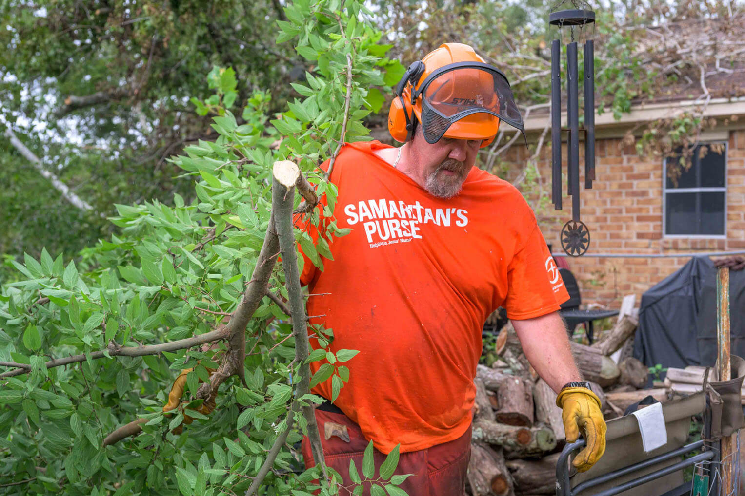 Jason Frazier assists at a home overwhelmed with tree debris by cutting up limbs and pulling them out.