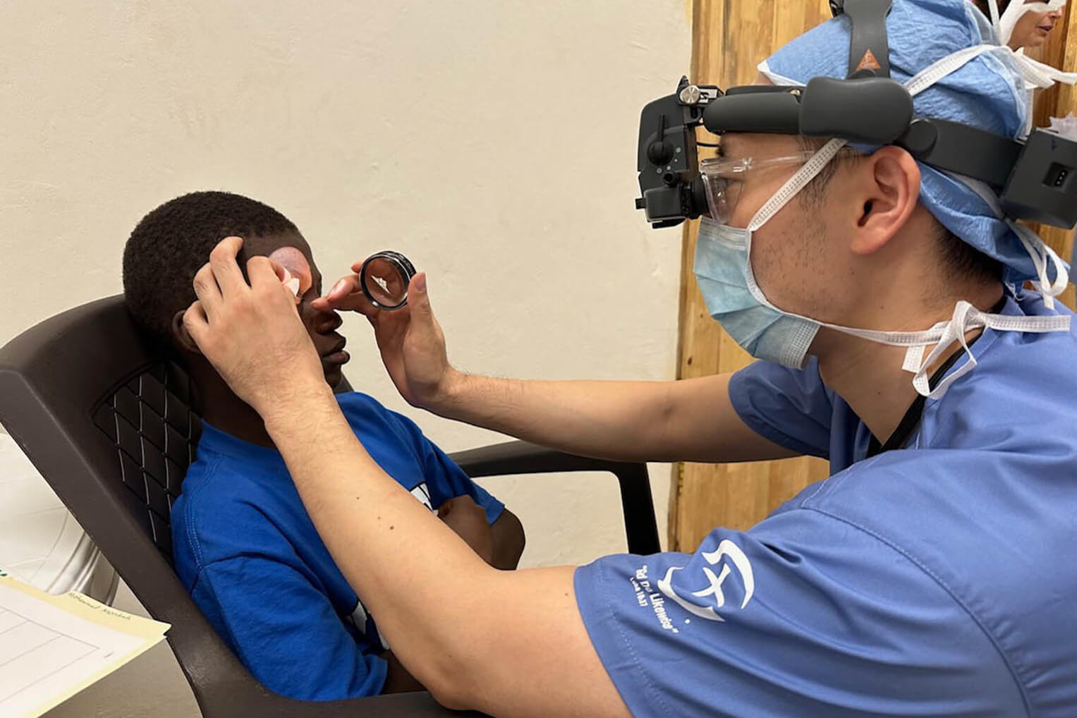 A medical team member examines a patient's eyes prior to surgery.