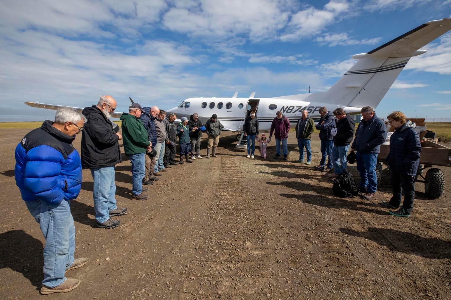 Samson Weston, at far left, prays with newly arriving volunteers to Nunivak Island.