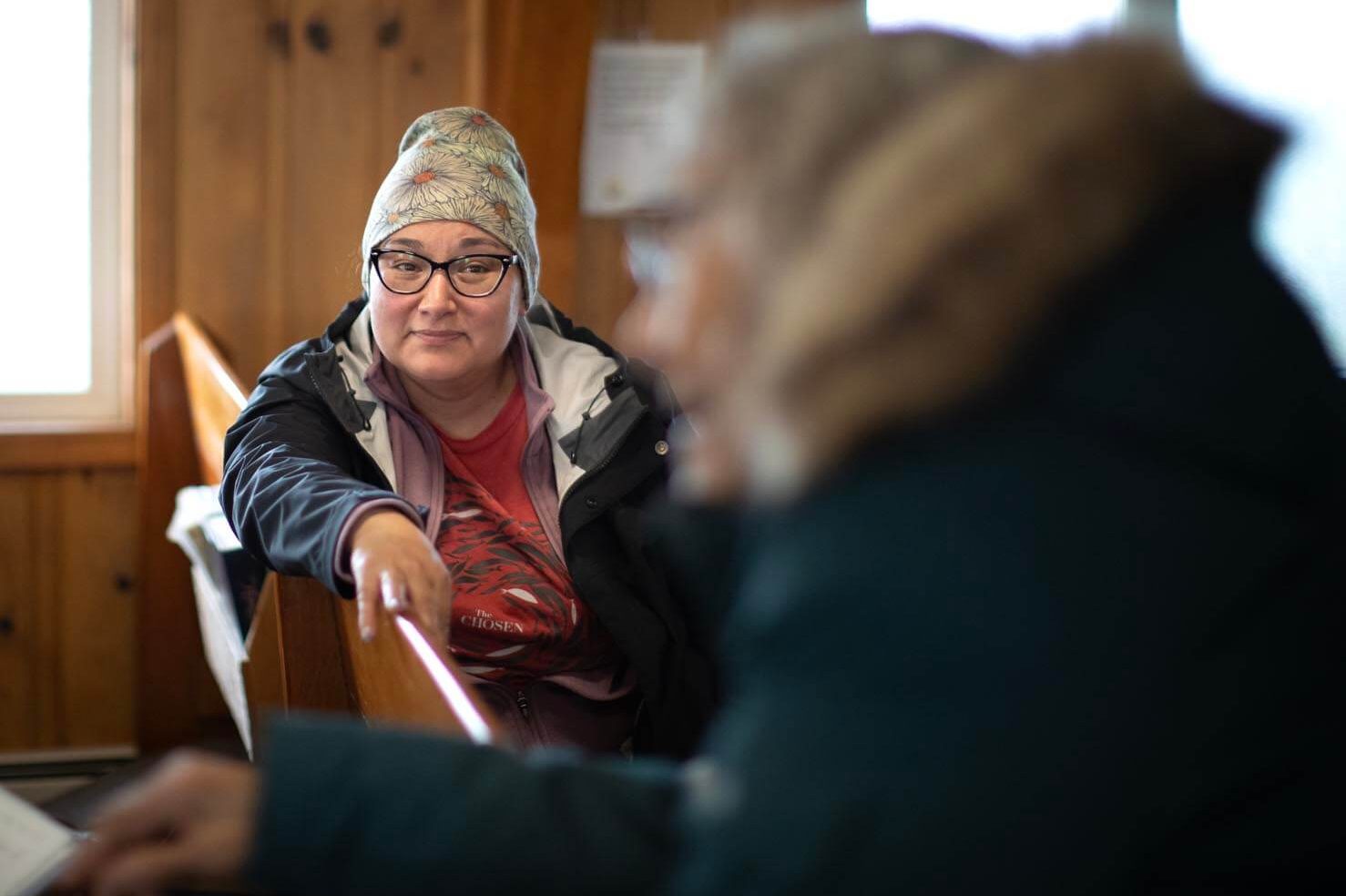 Bea Kiokun sits in a pew at Mekoryuk's second-built church, with her mother, Prudy, in the foreground.