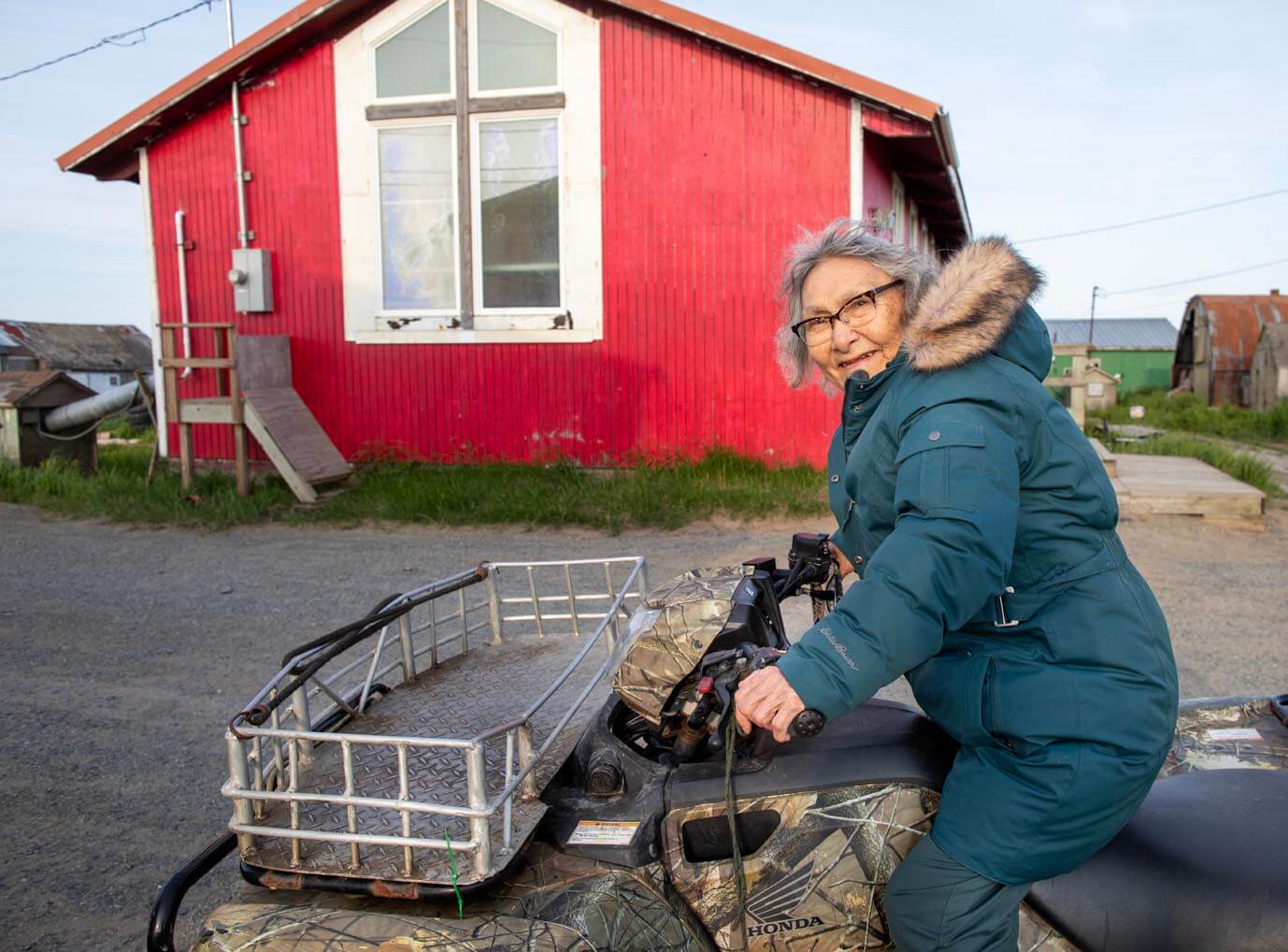 Prudy Olrun drives her four-wheeler around town past the older church building.