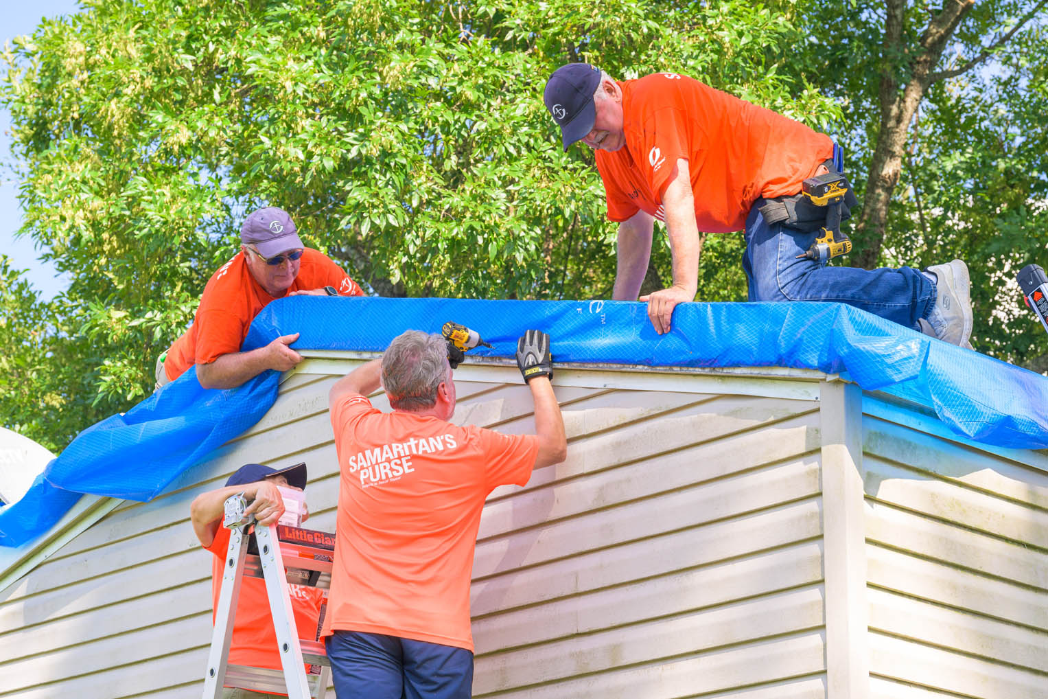 Volunteers work meticulously to ensure the tarp provides reliable protection from the elements.