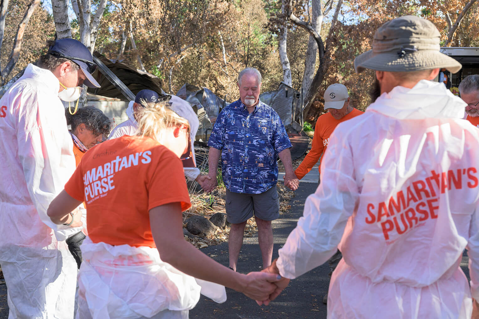 Volunteers pray with Lynn Smith, whose home was consumed by the Park Fire, after working to salvage belongings at his property.