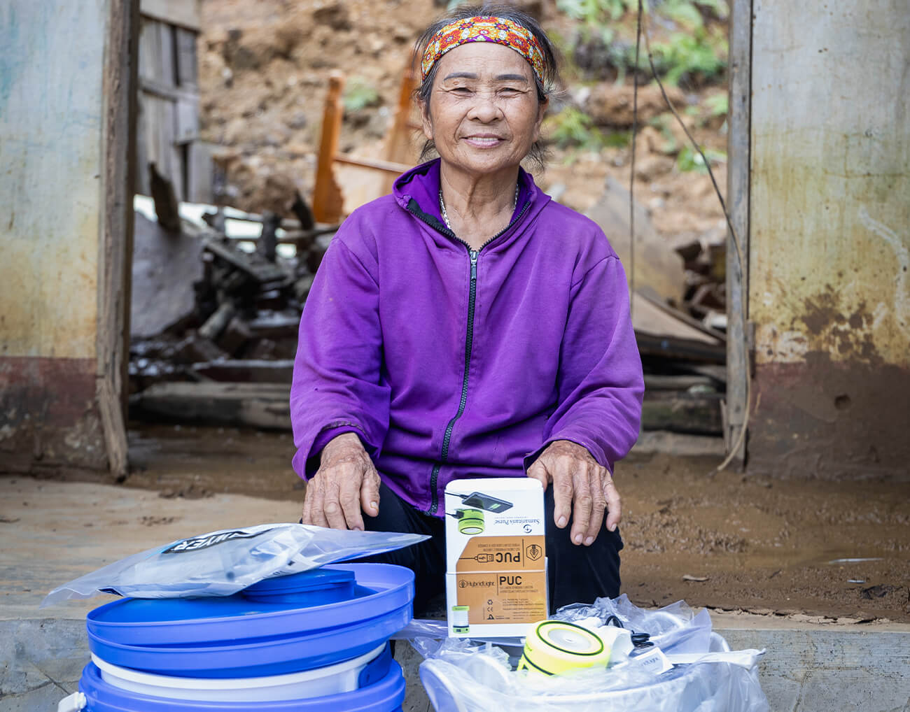 Tran sits behind her supplies she received from Samaritan's Purse--a household water filtration system, a solar-powered light, and a kitchen kit.