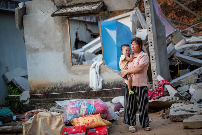 Pho stands with her young child on the foundation of what once was her home, crumbled by landslides and floodwaters. 