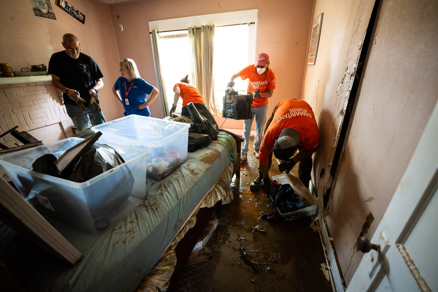 Michael Dixon, far left, picks through the few valuables in his bedroom that endured Hurricane Helene. 