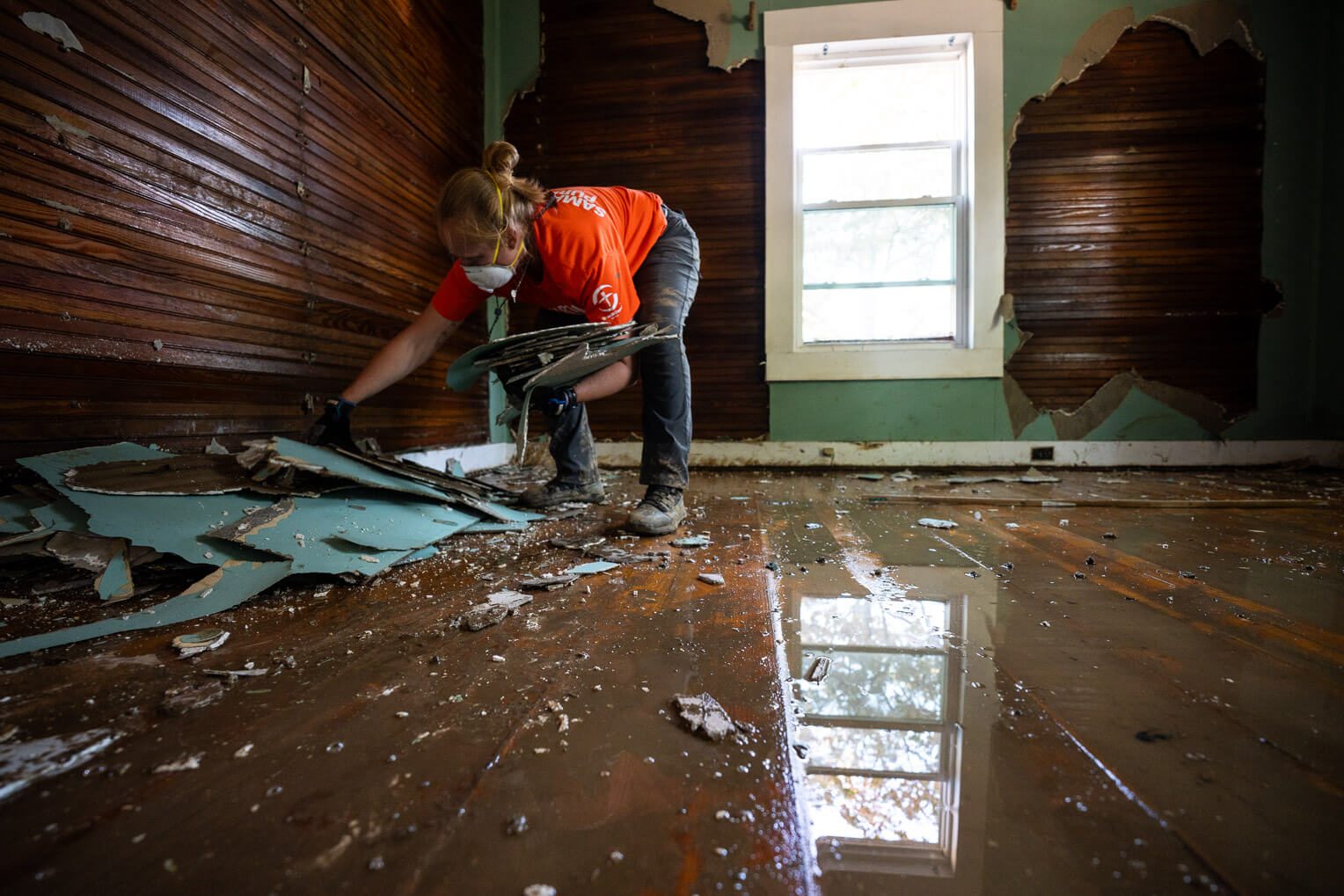 A volunteer finishes picking up the last pieces of drywall in the Dixons' guest bedroom.