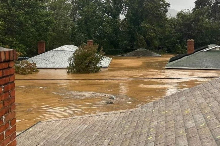 This photo provided by the Dixons shows their home, the left rooftop, underwater. Their neighbors across the street were rescued shortly after capturing this picture. 