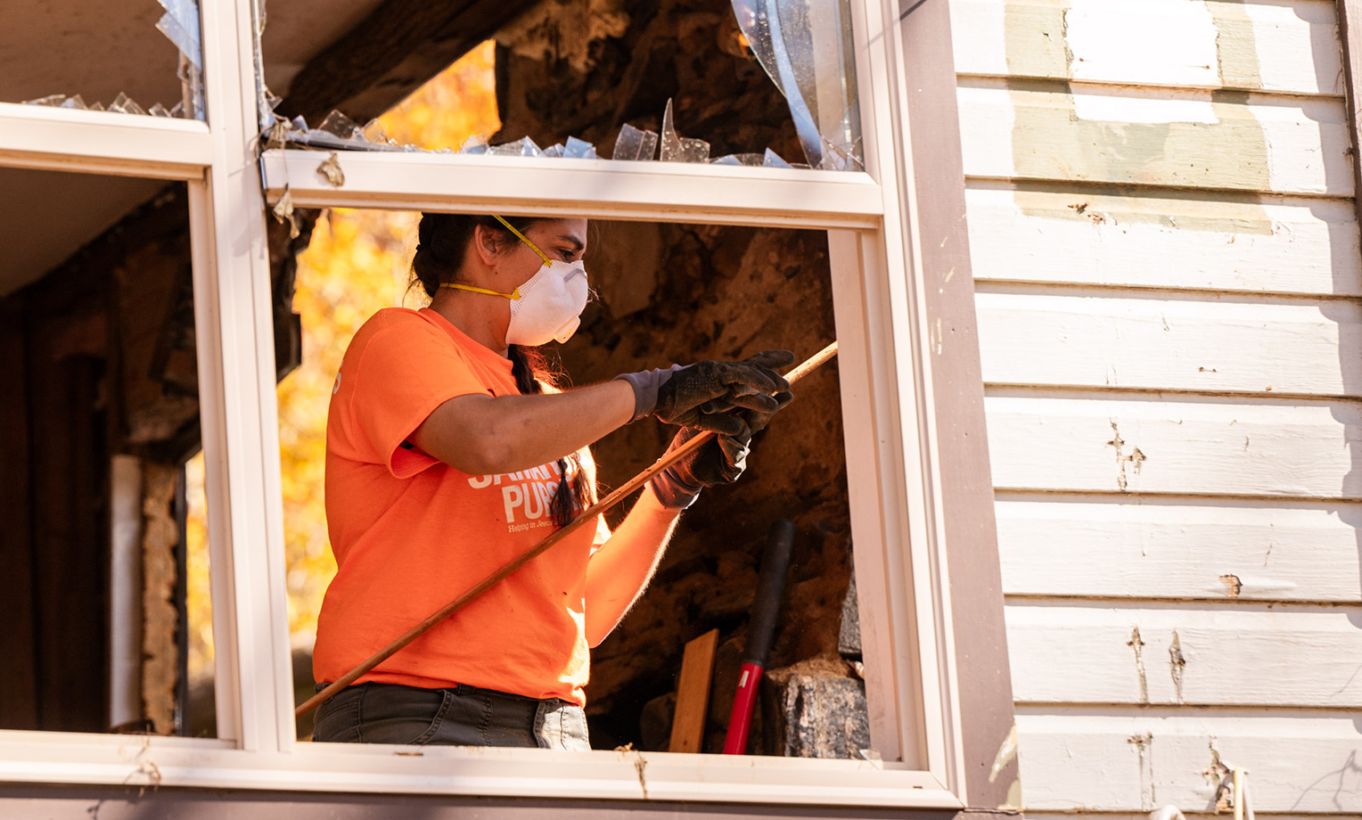 A volunteer works carefully to remove parts of a damaged wall where water rushed through. On the day of the storm, the South Toe River became a swelling debris flow of boulders, trees, and other upstream debris sweeping through the surrounding communities.