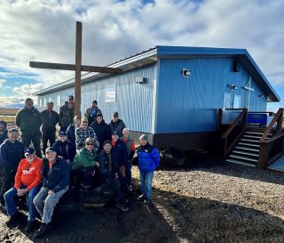 Samaritan's Purse staff, volunteers, and community members with the newly finished church in Mekoryuk.