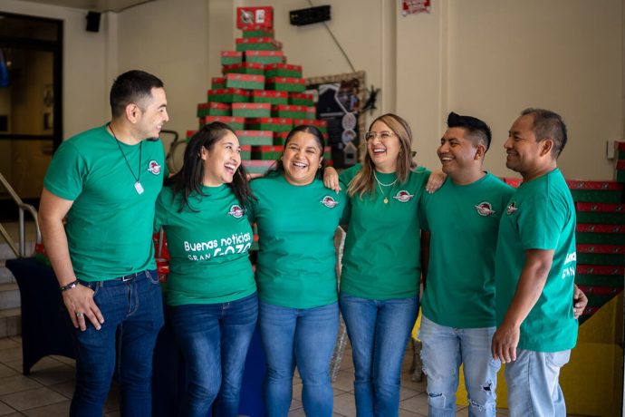 Saúl, Claudia, Alby, Carla, Ángel y Gustavo (de izquierda a derecha) muestran su alegría mientras animan a sus compañeros de iglesia a empacar cajas de regalos en esta temporada navideña.