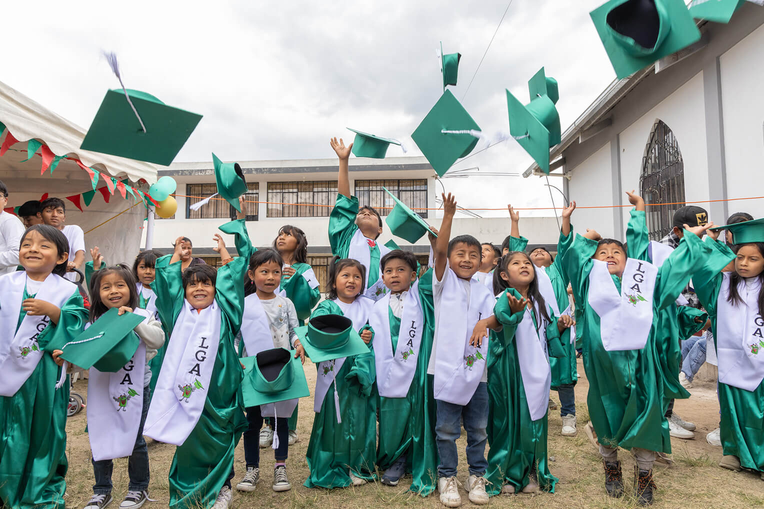 Boys and girls toss their caps in the air after graduating from The Greatest Journey.