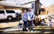 Brandt Justice (right) and his father Gary Justice stand in the Justices' yard where flood water came through, filling their home. Our volunteers helped clean out damaged belongings, walls, and flooring.