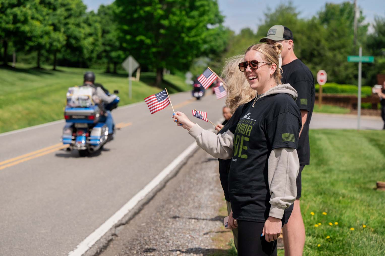 Families wave American flags as riders pass by in a show of support.