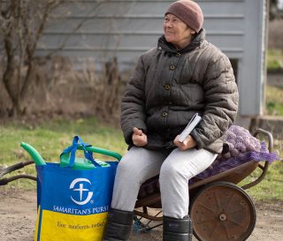 Ukrainian woman sits on wheelbarrow full of seed potatoes