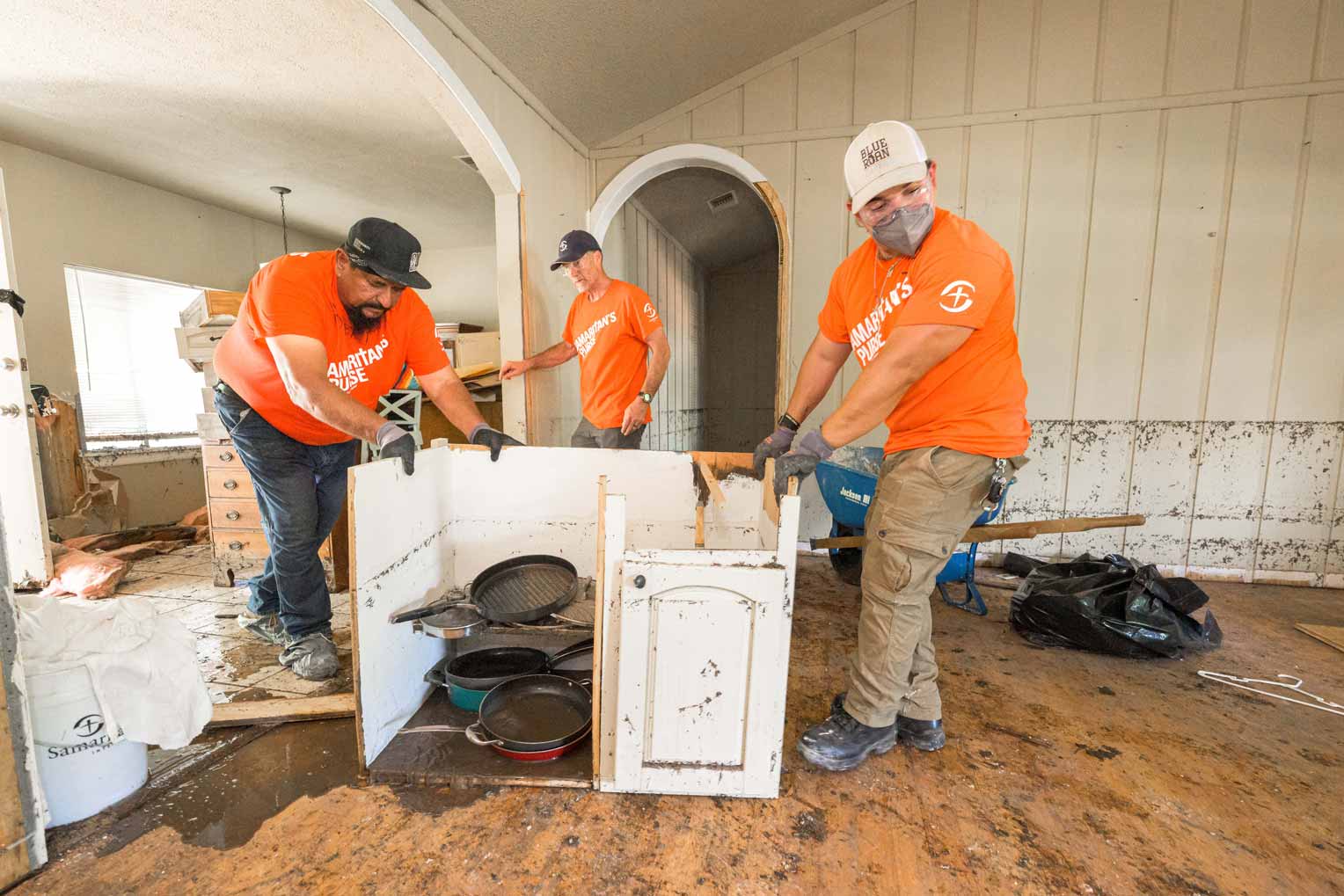 Volunteers remove furniture and other damaged belongings. The dark line along the wall tells of the height the water reached inside the house.