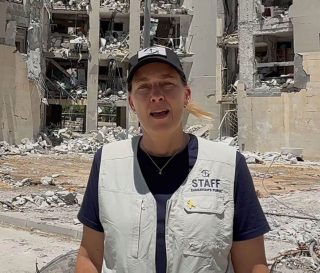 Staff member in front of destroyed building