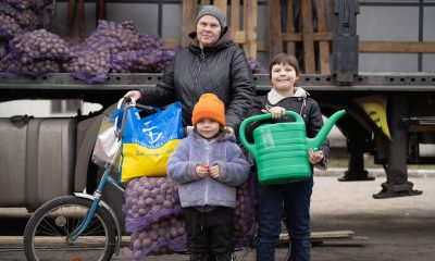 Mother and two children load bicycle with seed potatoes and watering can