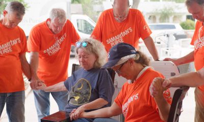 Samaritan's Purse volunteers, with Helping in Jesus' Name orange shirts, gave a Bible to a local resident and prayed with her in San Angelo, Texas, where flash flooding hit the community in Tom Green County on July Fourth.